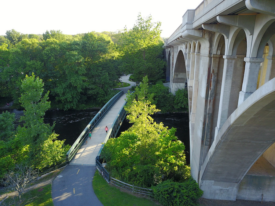 The Blackstone River Greenway in Rhode Island, with a wide paved path alongside a flowing river and green banks
