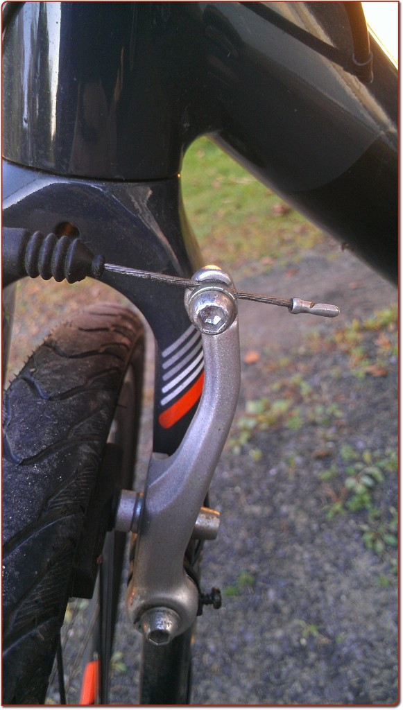 Close-up of the cable length setting screw (cable anchor bolt) at the brake caliper
