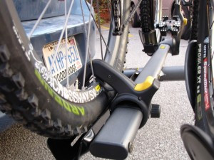 A close-up view of the Saris CycleOn Pro bike rack's wheel holders, showcasing the adjustable straps and cradles designed to secure bicycle wheels of various sizes. The rack is constructed from black metal and plastic components, emphasizing its robust and adaptable design for different types of bikes.