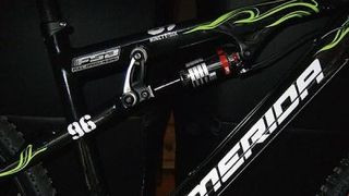 A full-suspension Merida mountain bike is positioned outdoors, highlighting its advanced suspension system.
