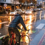 Someone on a bicycle with a downpour of rain happening around them. They are wearing full rain gear.