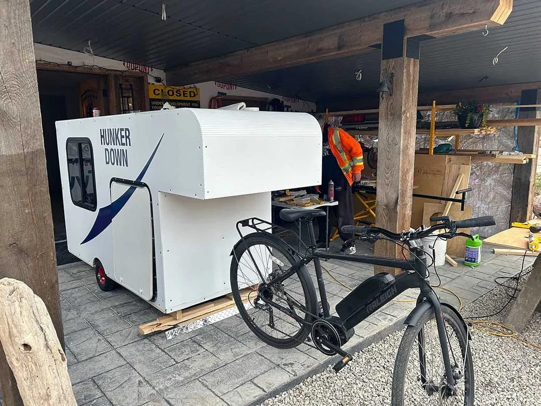 The DIY bike camper taking shape during the construction phase, showing the assembly of the frame and body panels.