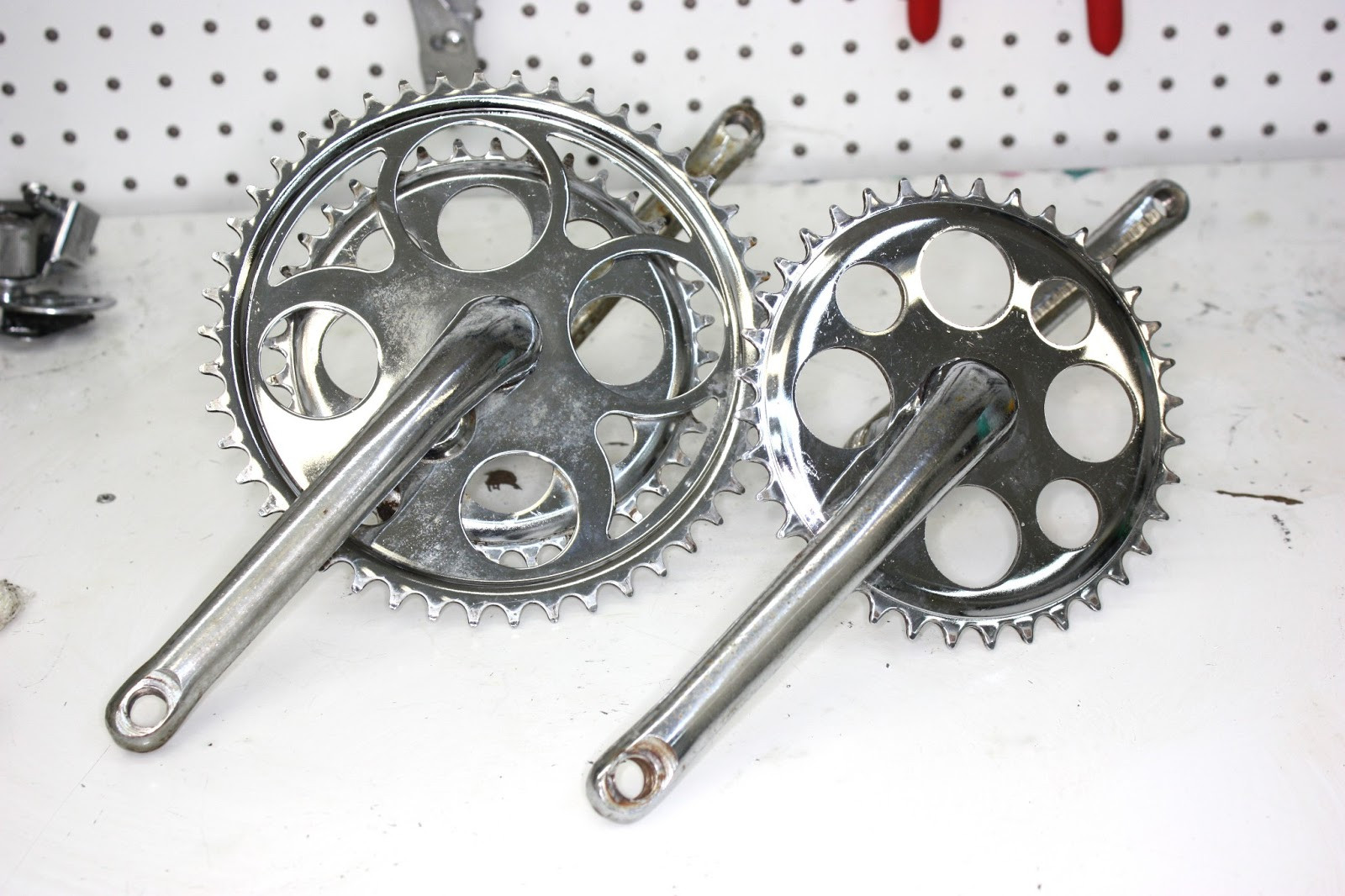 Crank arms of the Steve Schwinn bike cleaned but not yet polished, showing initial improvement.