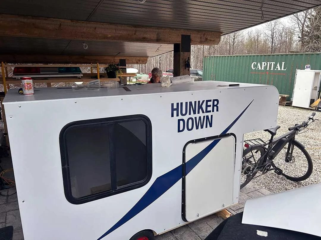 Side view of the partially built DIY bike camper trailer, highlighting the coroplast shell and overall shape before final touches.