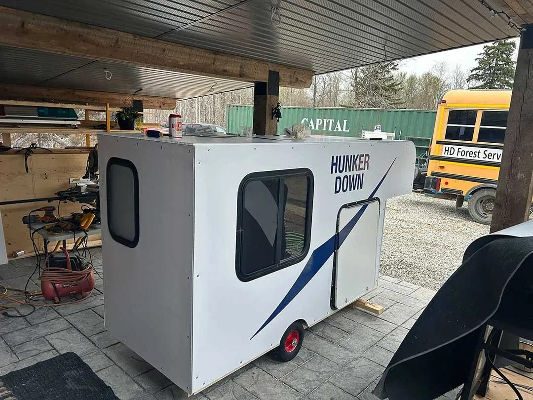 Rear view of the DIY bike trailer camper during construction, showcasing the hatch door and frame before completion.