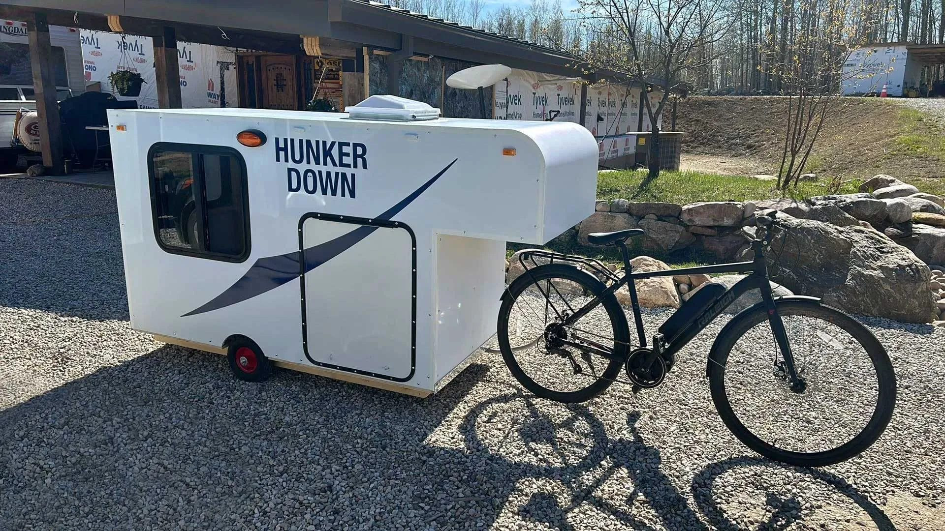 First bike hitch-up of the DIY bike trailer camper to the bicycle, revealing the initial setup before hitch adjustments.