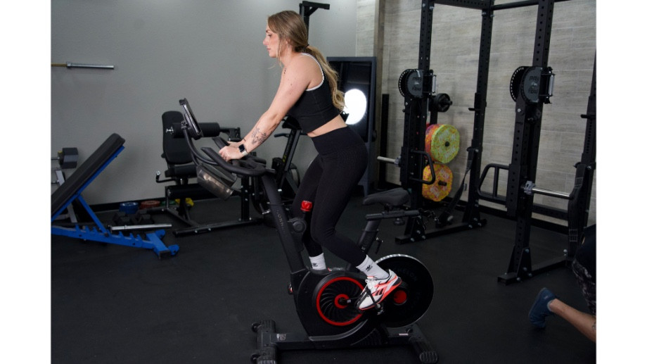 Woman standing and cycling on the Echelon EX-5 bike, showcasing its versatility.
