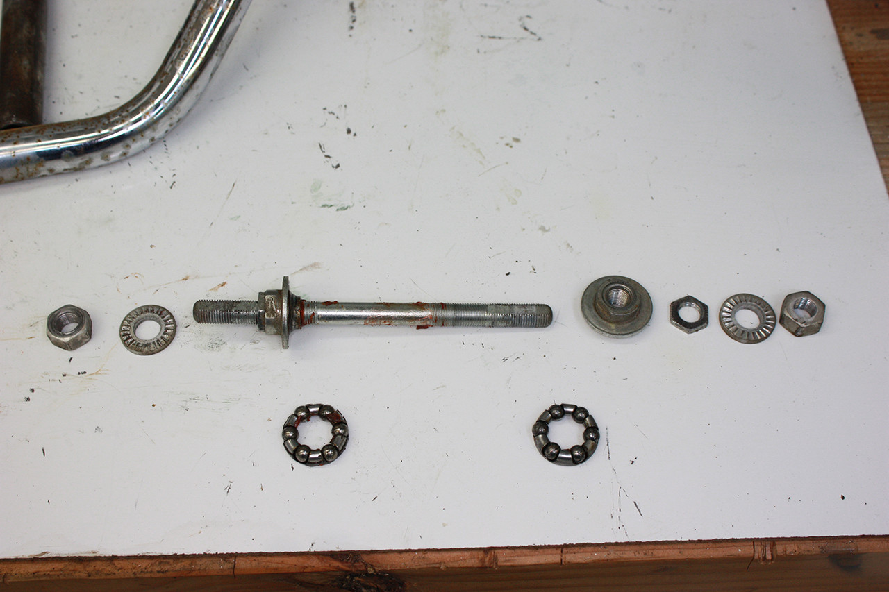 Front wheel axle components of the Schwinn Twinn Tandem before cleaning, exhibiting old grease and grime.