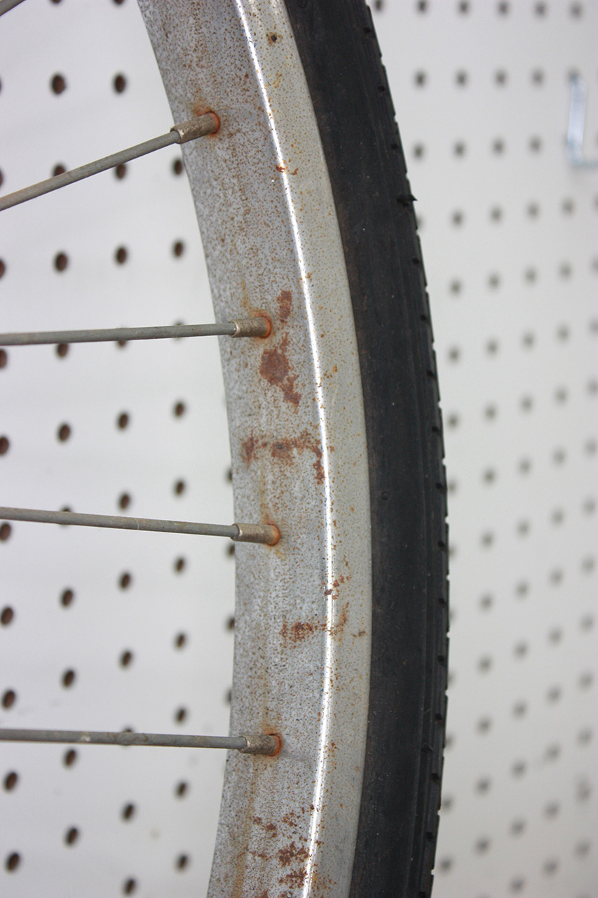 Front wheel rim of the vintage Schwinn tandem before restoration, exhibiting rust and corrosion.