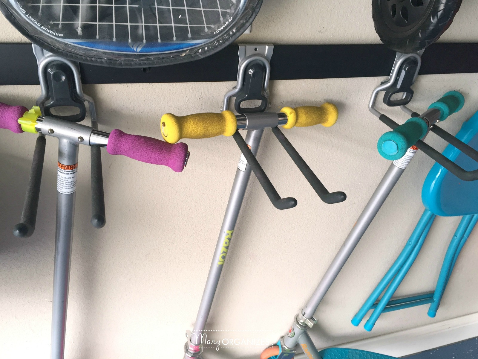 Scooters hanging on multi-purpose hooks in a garage.