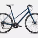 Woman riding Specialized Sirrus 2.0 Step-Through hybrid bike in urban environment