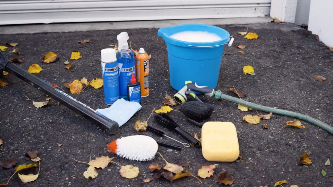 Bike washing supplies including bucket, soap, brushes, hose, and rags