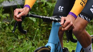 Mathieu Van der Poel is captured riding a Canyon Aeroad road bike, focusing on the handlebar area and his hand position.