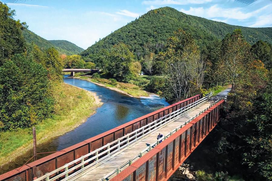 A cyclist enjoys the scenic Pine Creek Rail Trail in Pennsylvania, riding through the 'Grand Canyon of Pennsylvania'.