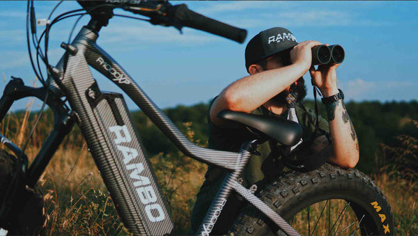 alt text: Rambo electric hunting bike in woodland setting, showcasing its stealth and outdoor readiness.