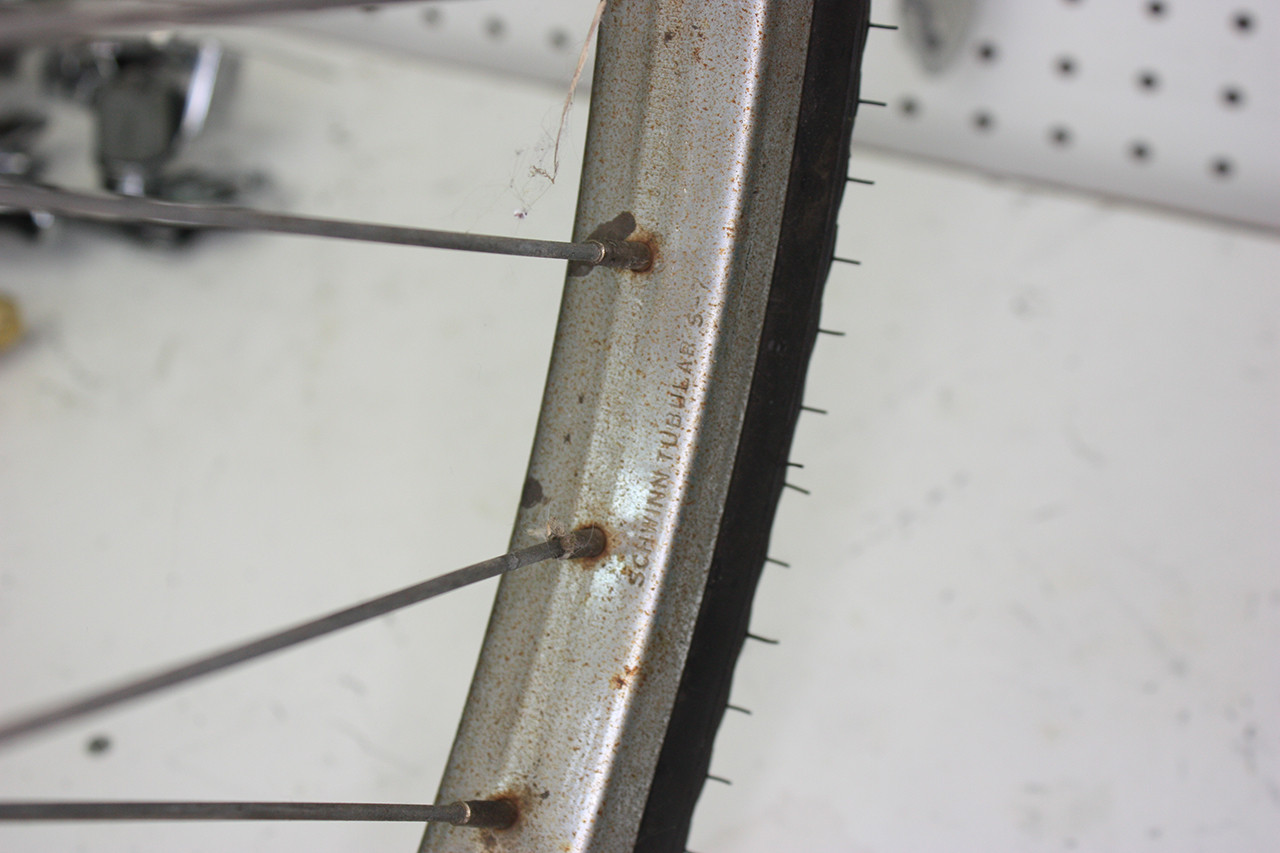 Rear wheel rim of the vintage Schwinn tandem before cleaning and polishing, displaying rust and wear.