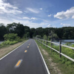 Cyclists enjoying the East Bay Bike Path in Rhode Island, with scenic coastal views