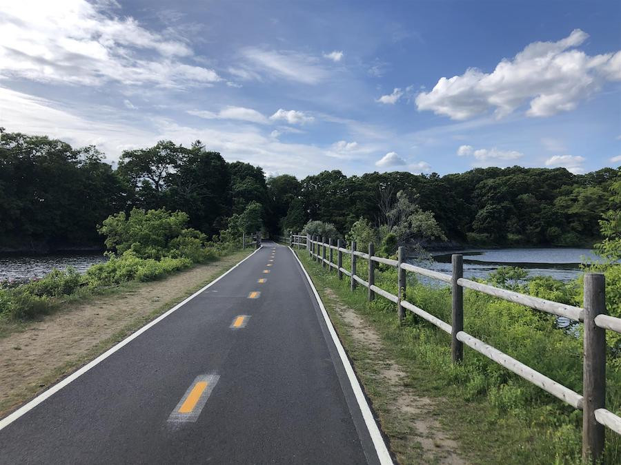 Cyclists enjoying the East Bay Bike Path in Rhode Island, with scenic coastal views