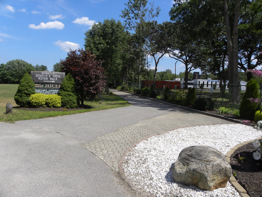 The JAYCEE Arboretum and Senator Roch Riverwalk in Rhode Island, with a paved path through a riverside park setting