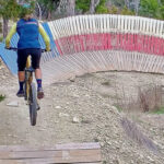 Mountain biker executes a jump in front of the iconic Texas flag wall ride at Spider Mountain Bike Park, Texas