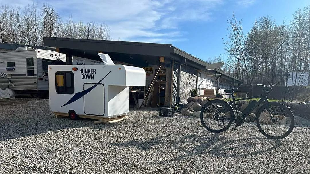 Testing the DIY bike trailer camper with the bicycle, indicating the need for hitch redesign for improved functionality and stability.