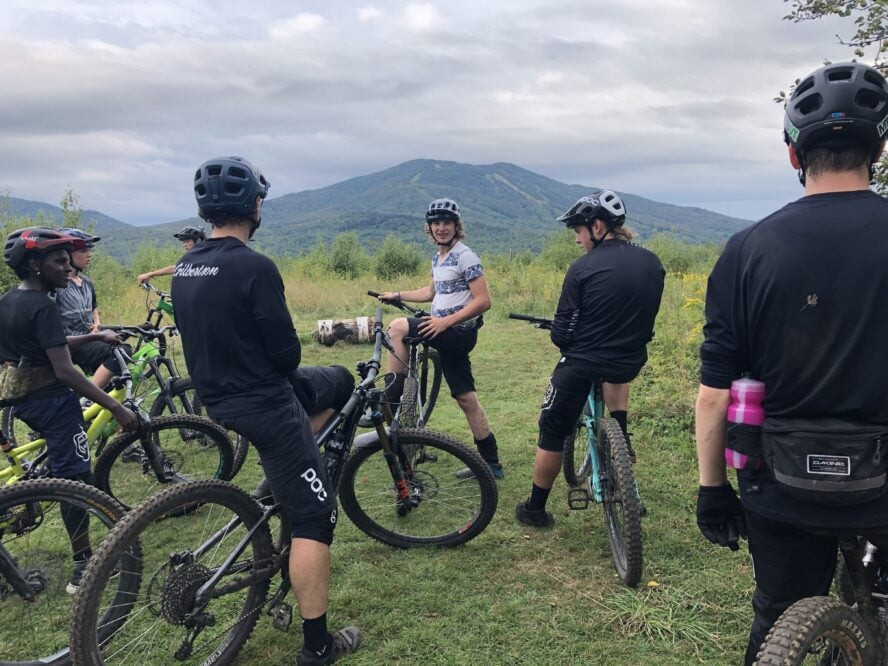 A group of mountain bikers discussing their route before heading out, highlighting the social and supportive environment for beginner mountain bikers at Kingdom Trails.