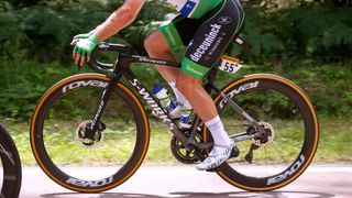 A close-up shot captures the detailed components of a high-end road bike at the Tour de France, emphasizing its cost and performance focus.