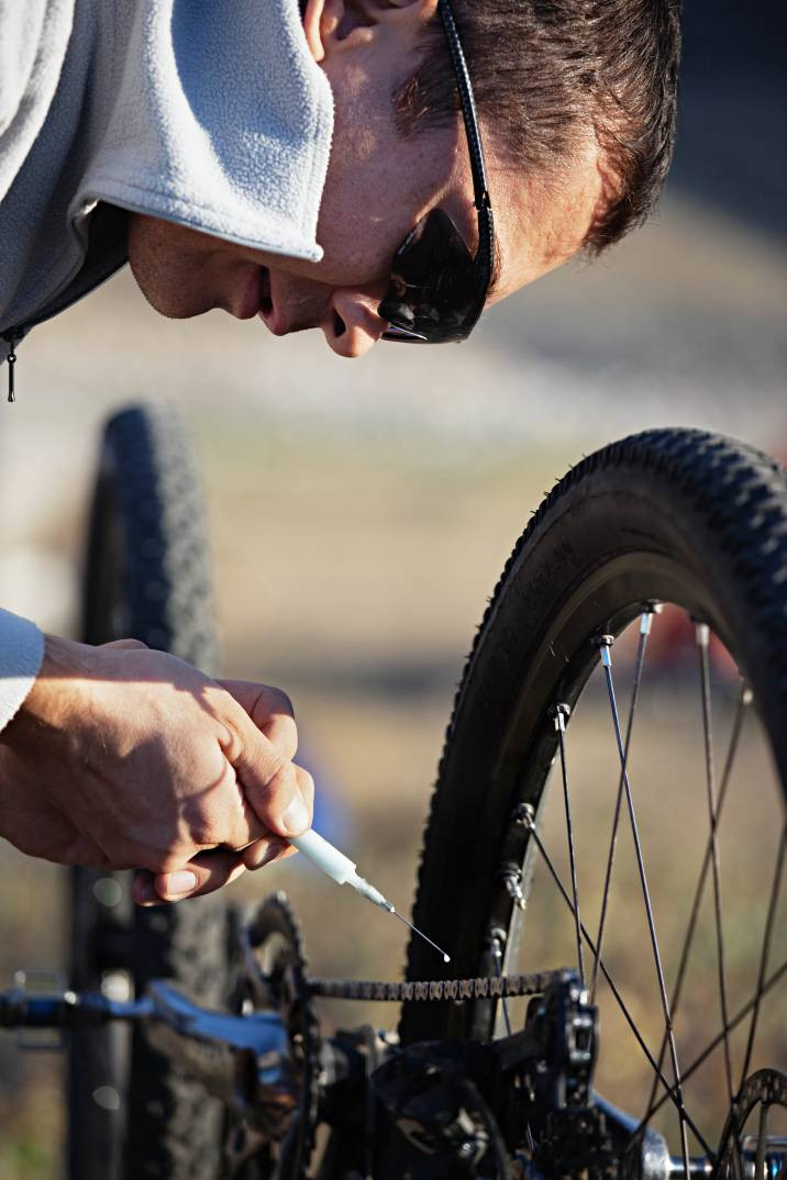 A bicycle mechanic lubricating a chain