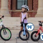 Three kids, each on a balance bike. One has 16 inch wheels, one has 14 inch wheels, and one has 12 inch wheels.