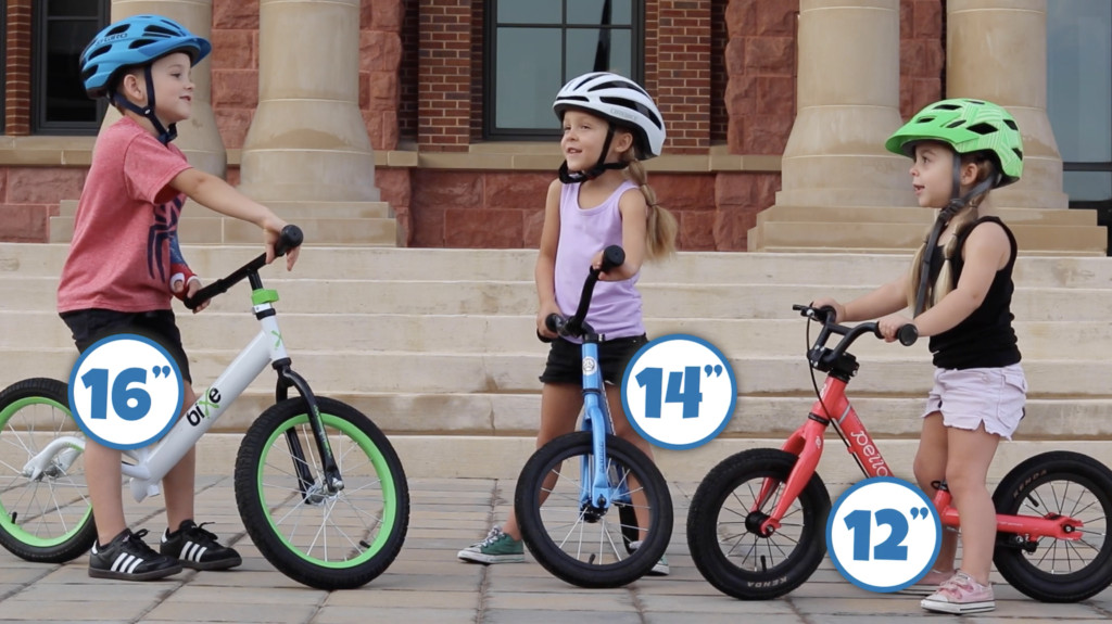 Three kids, each on a balance bike. One has 16 inch wheels, one has 14 inch wheels, and one has 12 inch wheels.