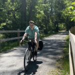 Man riding a bike on a bicycle trail on his way to bike camp.