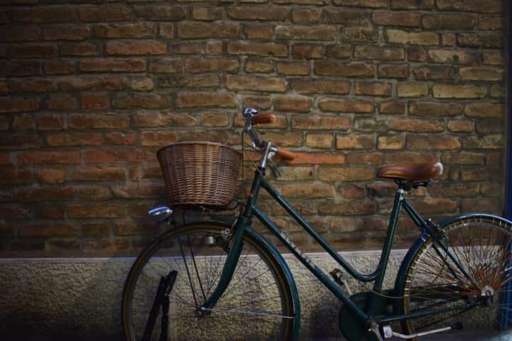 Bike with a basket leaning against an exposed brick wall