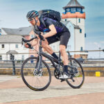 A male cycling on a blue bicycle on the harbour-side