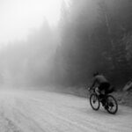 Mountain biker riding through forest trails, showcasing the bike's suspension and rugged tires