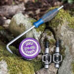 Removing mountain bike pedals using a wrench, focusing on the reverse thread of the non-drive side pedal