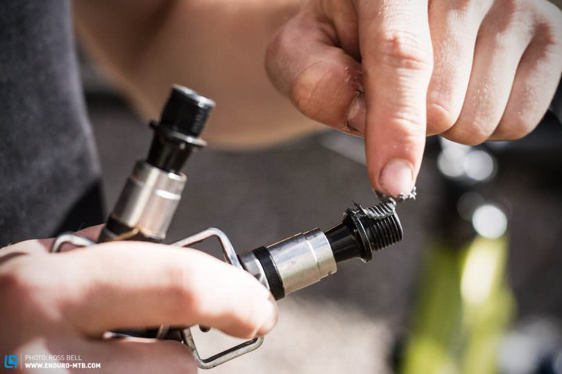 Applying anti-seize grease to mountain bike pedal threads, ensuring complete and even coverage