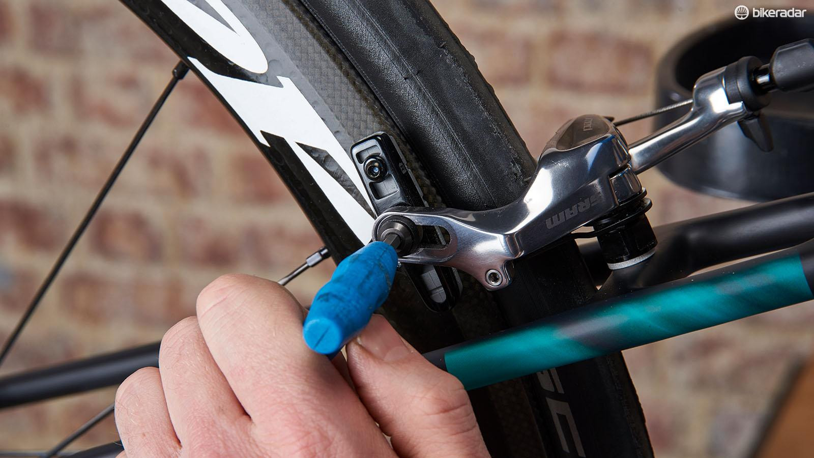 Close-up of a mechanic adjusting the brake cartridge on a bicycle rim brake.