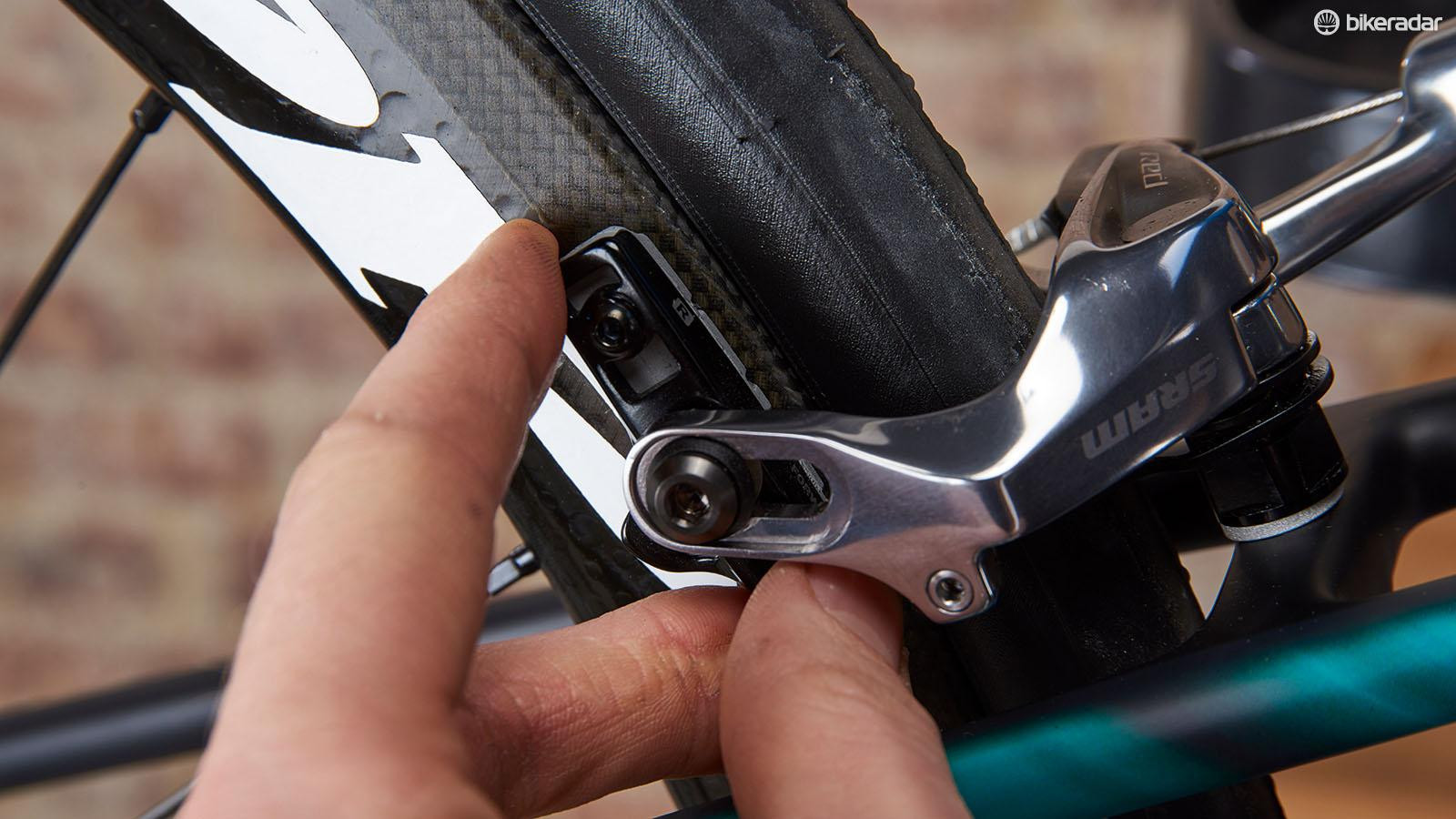 Mechanic lining up the brake pad with the rim on a bicycle.