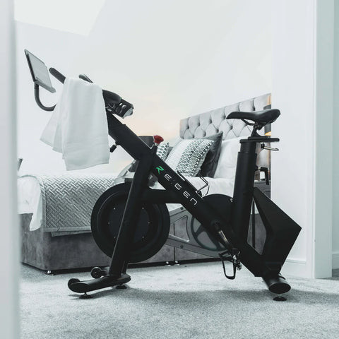 RE:GEN bike in a bedroom on a gray carpet with a white towel over the handlebars