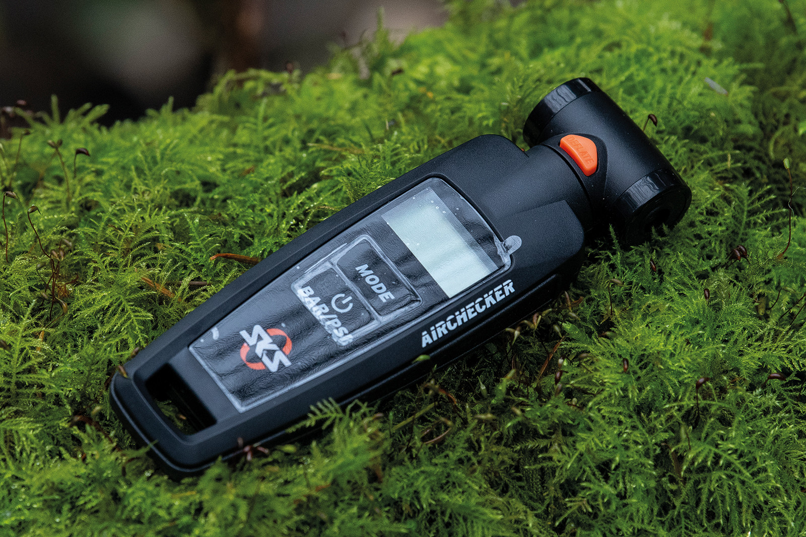 Cyclist checking gravel bike tire pressure with digital gauge