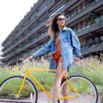 Girl on yellow single speed bikes wearing orange dress and denim jacket