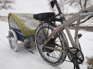Snowy bike path with a biker in the distance